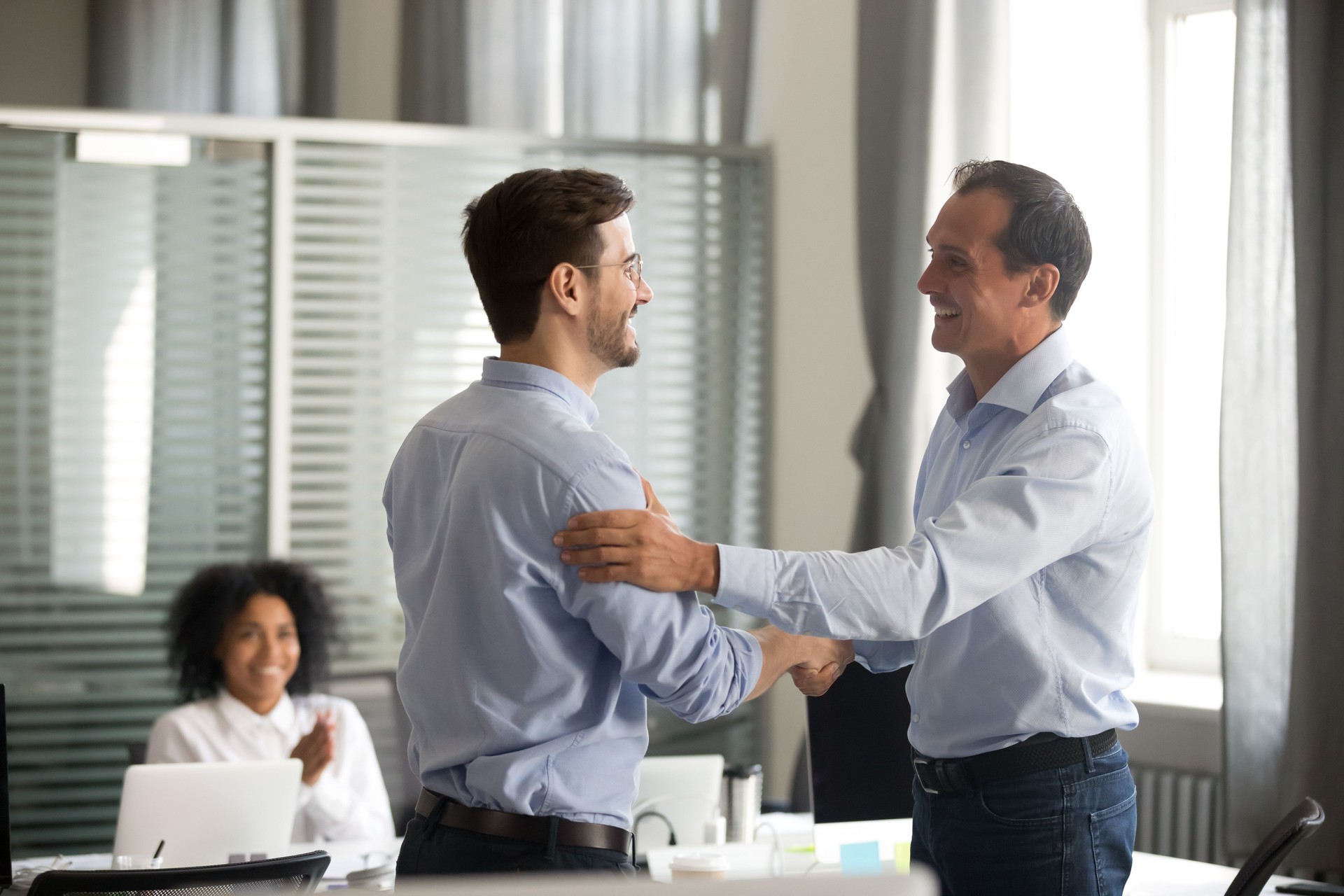 Smiling middle-aged ceo handshaking successful male worker showing respect